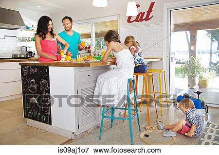 Stock Photo - Mid adult parents and three children preparing breakfast in kitchen. Fotosearch