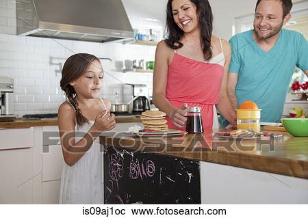 Mid adult parents tempting daughter with pancakes at breakfast bar View Large Photo Image Stock Image - Mid adult parents tempting daughter with pancakes at breakfast bar. Fotosearch