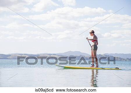 Mid adult woman stand up paddleboarding at sea View Large Photo Image Stock Image - Mid adult woman stand up paddleboarding at sea. Fotosearch