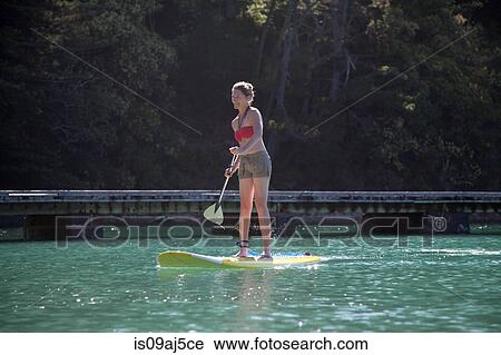 Mid adult woman stand up paddleboarding at sea View Large Photo Image Stock Image - Mid adult woman stand up paddleboarding at sea. Fotosearch