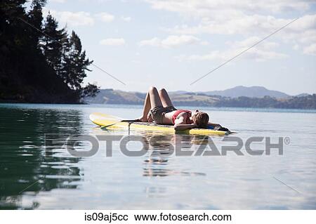 Mid adult woman sunbathing on paddleboard at sea View Large Photo Image Stock Image - Mid adult woman sunbathing on paddleboard at sea. Fotosearch