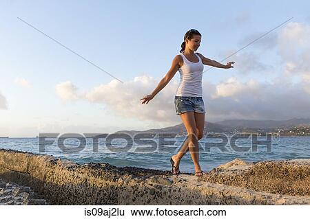Stock Photograph - Mid adult woman walking along pier, Spice Island beach resort, Grenada, Caribbean. Fotosearch
