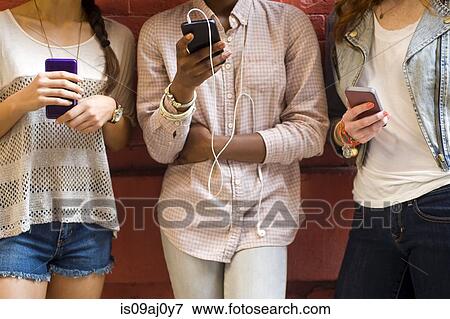 Mid section of three young women using mobile phones View Large Photo Image Stock Photo - Mid section of three young women using mobile phones. Fotosearch
