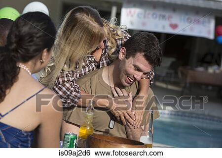 Stock Photograph - Mother hugging mid adult soldier son at homecoming party. Fotosearch