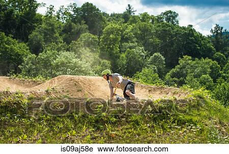 Stock Image - Mountain biker speeding around bend on rural pump track. Fotosearch
