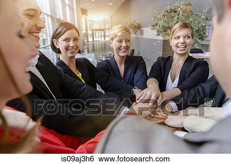 Over shoulder view of business team placing hands on top of each other in office View Large Photo Image Stock Photograph - Over shoulder view of business team placing hands on top of each other in office. Fotosearch