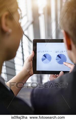 Over shoulder view of businesswoman and man using touchscreen on digital tablet in office View Large Photo Image Stock Image - Over shoulder view of businesswoman and man using touchscreen on digital tablet in office. Fotosearch