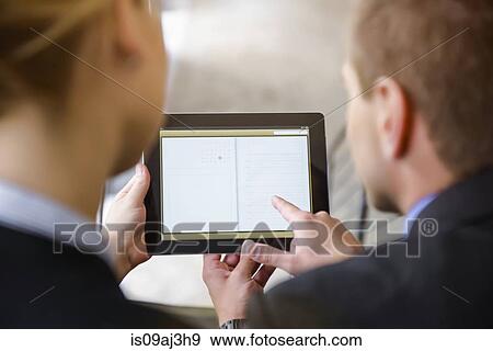 Over shoulder view of businesswoman and man using digital tablet in office View Large Photo Image Stock Photo - Over shoulder view of businesswoman and man using digital tablet in office. Fotosearch