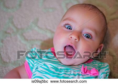 Stock Image - Overhead portrait of wide eyed baby girl. Fotosearch