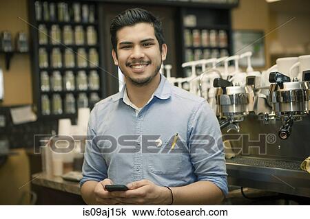 Stock Image - Portrait of barista with smartphone in cafe. Fotosearch