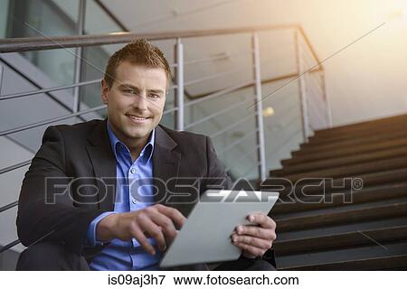 Portrait of businessman using digital tablet on office stairway View Large Photo Image Stock Photo - Portrait of businessman using digital tablet on office stairway. Fotosearch