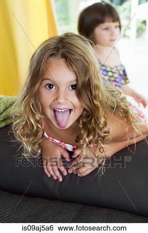 Stock Photograph - Portrait of confident girl sticking her tongue out. Fotosearch