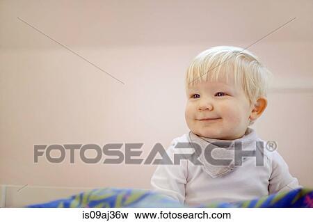 Portrait of cute fourteen month old baby boy sitting on duvet View Large Photo Image Stock Photo - Portrait of cute fourteen month old baby boy sitting on duvet. Fotosearch