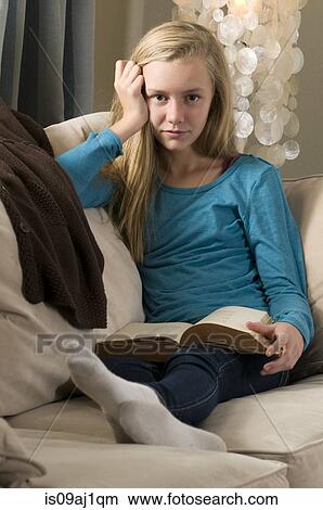 Portrait of displeased pre adolescent girl reading book on sofa View Large Photo Image Picture - Portrait of displeased pre adolescent girl reading book on sofa. Fotosearch