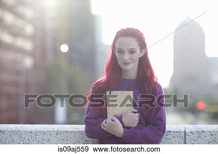 Stock Photo - Portrait of pink haired young woman with notebook on city rooftop. Fotosearch