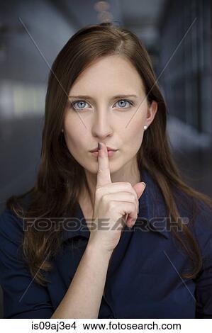 Portrait of serious young businesswoman with finger on lips in office View Large Photo Image Picture - Portrait of serious young businesswoman with finger on lips in office. Fotosearch
