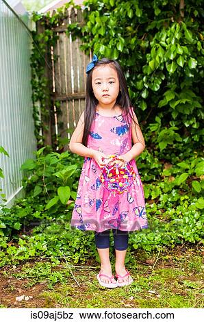 Portrait of serious young girl in garden with toy View Large Photo Image Stock Photo - Portrait of serious young girl in garden with toy. Fotosearch