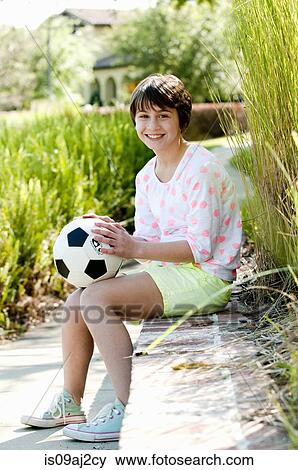 Portrait of ten year old girl sitting on park wall with soccer ball View Large Photo Image Stock Photo - Portrait of ten year old girl sitting on park wall with soccer ball. Fotosearch
