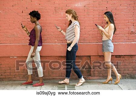 Portrait of three young women using mobile phones View Large Photo Image Stock Image - Portrait of three young women using mobile phones. Fotosearch