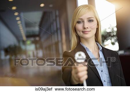 Stock Image - Portrait of young businesswoman holding up network power cable in office. Fotosearch