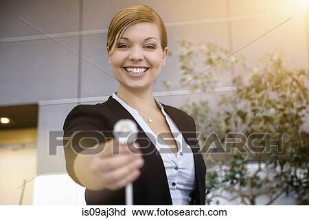 Stock Image - Portrait of young businesswoman holding up cable in office. Fotosearch