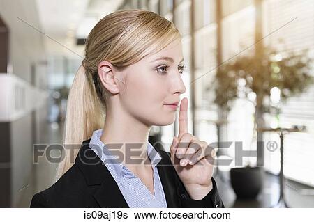 Portrait of young businesswoman holding finger up to lips View Large Photo Image Stock Photograph - Portrait of young businesswoman holding finger up to lips. Fotosearch
