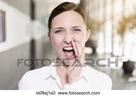 Stock Image - Portrait of young businesswoman shouting in office. Fotosearch