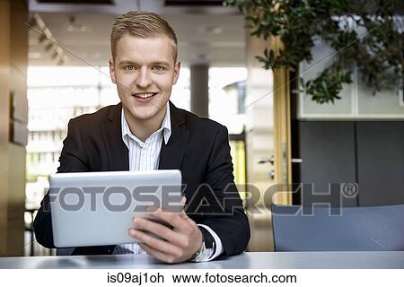 Portrait of young man in office using touchscreen on digital tablet View Large Photo Image Stock Image - Portrait of young man in office using touchscreen on digital tablet. Fotosearch