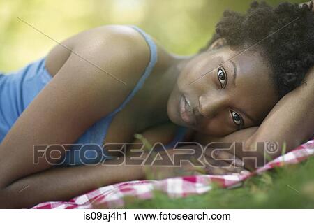 Portrait of young woman lying on side in park View Large Photo Image Stock Image - Portrait of young woman lying on side in park. Fotosearch
