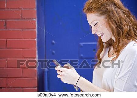 Picture - Portrait of young woman using mobile phone. Fotosearch