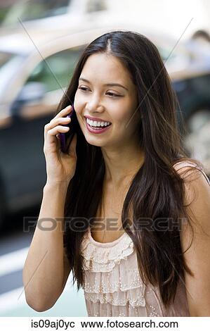 Stock Image - Portrait of young woman using mobile phone. Fotosearch