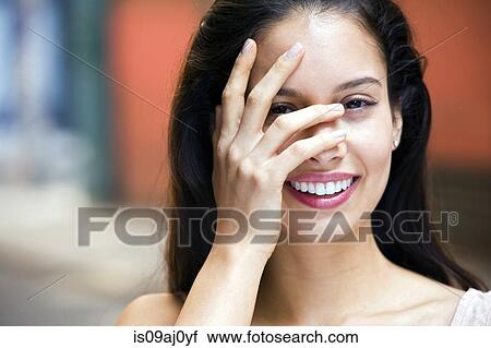 Stock Image - Portrait of young woman with hand covering face. Fotosearch