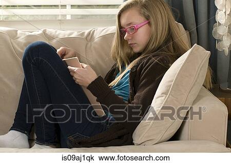 Pre adolescent girl reading book on sofa View Large Photo Image Stock Image - Pre adolescent girl reading book on sofa. Fotosearch