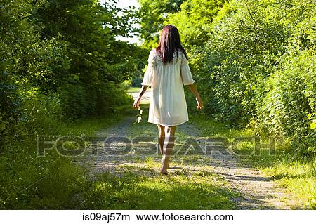 Picture - Rear view of young woman strolling barefoot along rural track, Delaware Canal State Park, New Hope, Pennsylvania, USA. Fotosearch