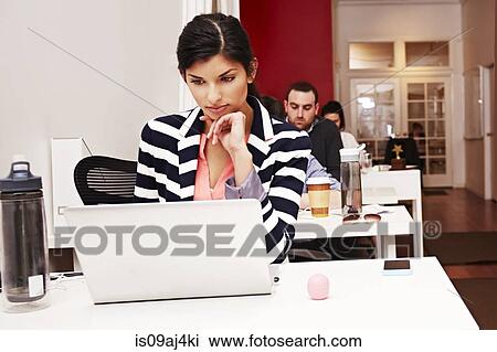 Stock Image - Row of people working on laptops in office. Fotosearch