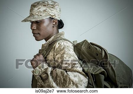 Stock Photo - Side view studio portrait of female soldier with rucksack looking down. Fotosearch