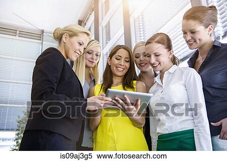 Six female businesswomen looking down at digital tablet in office View Large Photo Image Stock Photography - Six female businesswomen looking down at digital tablet in office. Fotosearch