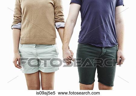 Stock Photography - Studio cropped shot of young couple holding hands. Fotosearch