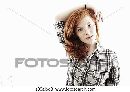 Stock Image - Studio portrait of young woman with arm over head. Fotosearch