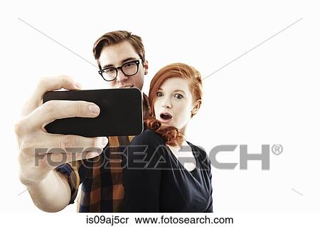 Stock Photography - Studio shot of young couple posing for selfie on smartphone. Fotosearch