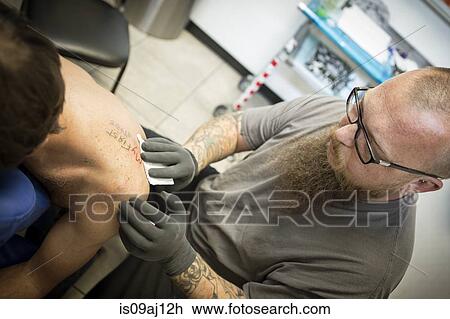 Tattoo artist finishing up a fresh tattoo View Large Photo Image Stock Image - Tattoo artist finishing up a fresh tattoo. Fotosearch