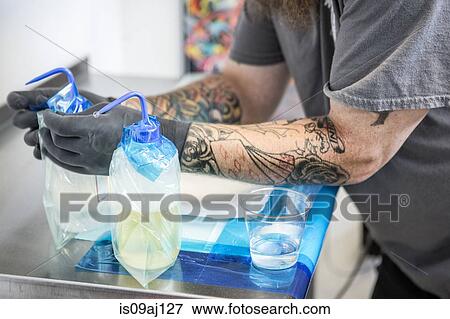 Tattoo artist preparing his work station with antiseptic solutions View Large Photo Image Stock Photo - Tattoo artist preparing his work station with antiseptic solutions. Fotosearch