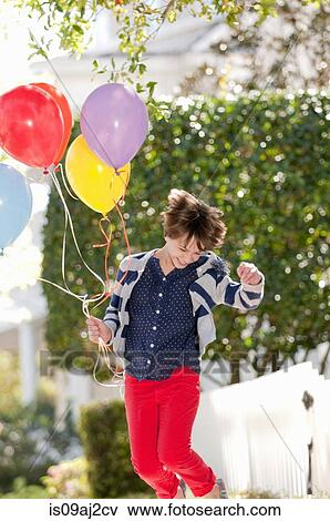 Stock Photo - Ten year old girl jumping excitedly with bunch of balloons. Fotosearch