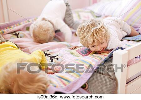 Three young brothers crawling face down on bed View Large Photo Image Stock Photography - Three young brothers crawling face down on bed. Fotosearch