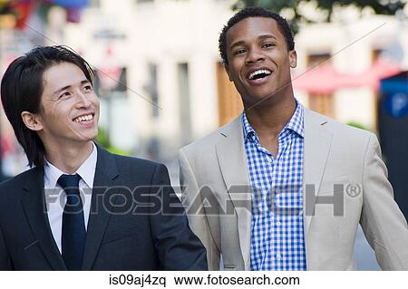 Stock Photography - Two businessmen chatting and laughing on city street. Fotosearch