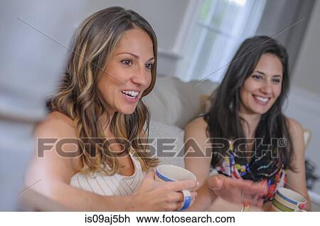 Two female friends chatting over coffee in sitting room View Large Photo Image Stock Image - Two female friends chatting over coffee in sitting room. Fotosearch