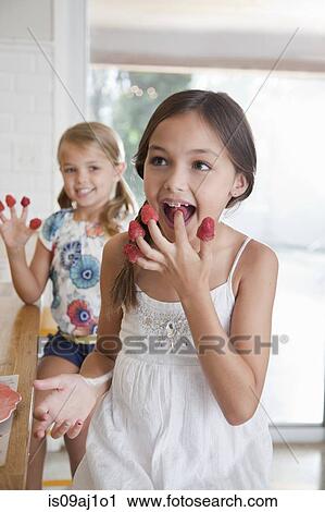 Two sisters with raspberries on their fingers in kitchen View Large Photo Image Stock Image - Two sisters with raspberries on their fingers in kitchen. Fotosearch