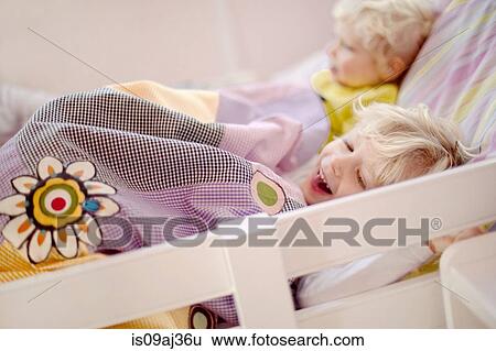 Stock Photograph - Two young brothers lying in bed, one laughing. Fotosearch