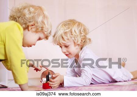 Two young brothers lying on rug gazing at snow globe View Large Photo Image Picture - Two young brothers lying on rug gazing at snow globe. Fotosearch