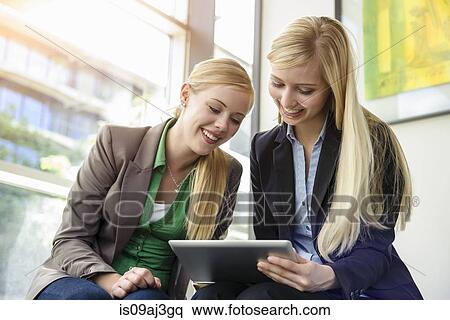 Two young businesswomen using digital tablet in office View Large Photo Image Stock Photography - Two young businesswomen using digital tablet in office. Fotosearch